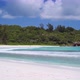 Anse Coco Beach on La Digue, Seychelles. Unrecognized Tourist Swimming in Shallow Blue Ocean Lagoon - VideoHive Item for Sale