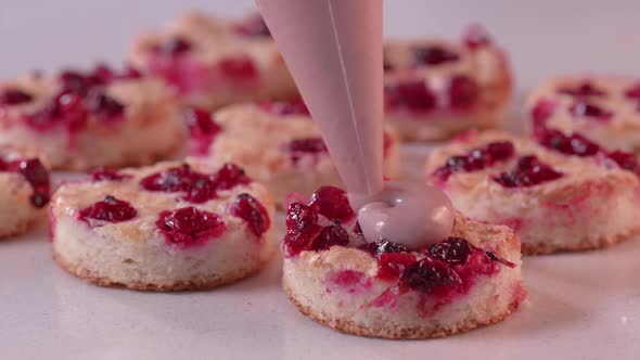 Pastry Chef Squeezes Pink Cream From a Pastry Bag Onto the Mini Cake alt