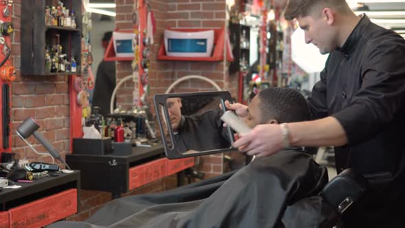 The Hairdresser Shows the Client the Result of the Haircut and Shave in the Hand Mirror alt