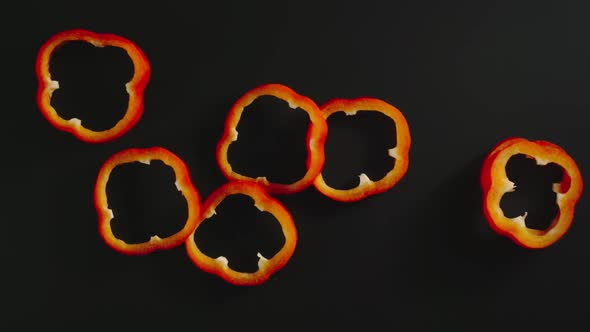 Fresh Red Bell Pepper Slices Falling Down On A Black Surface