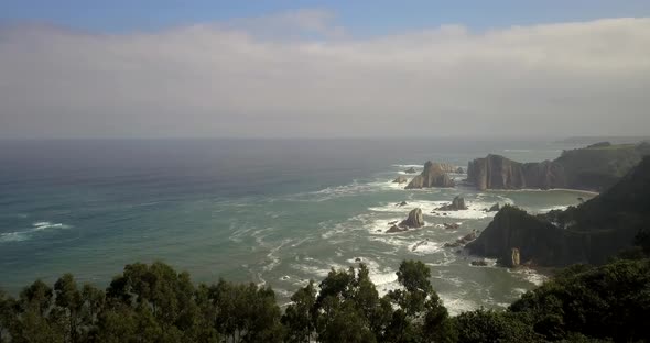 Drone flying forwards revealing Gueirua wild beach in cloudy day. Asturias coastline, Spain. alt