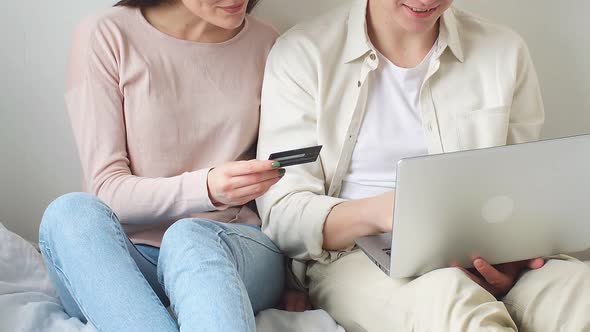 Man and a Woman in Casual Clothes Make Purchases Online Using a Laptop While at Home