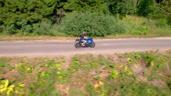 A Young Man Rides a Motorcycle Outside the City