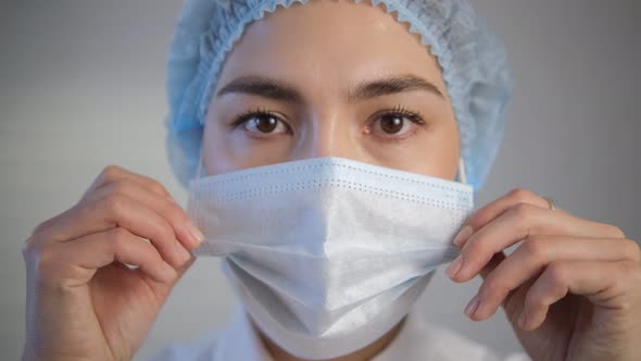 The female doctor removes the protective medical mask and puts it on alt