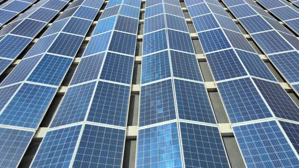 Aerial view of blue photovoltaic solar panels mounted on building roof for producing clean alt