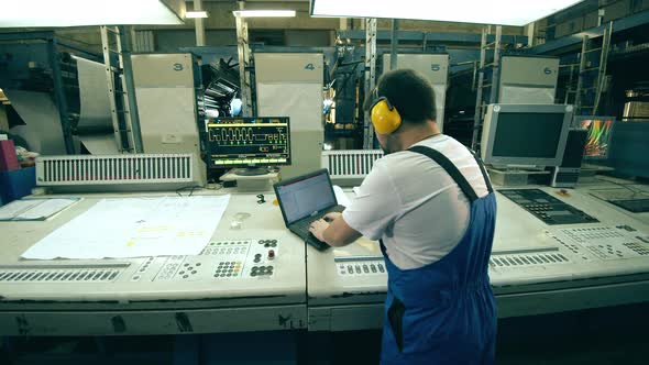Backside View of a Typography Worker Operating a Control Board alt