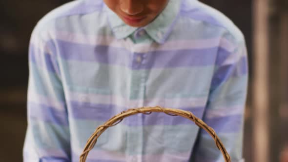 Happy asian boy holding basket of eggs in garden alt