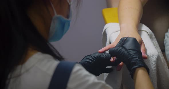 Young Brunette in a Beauty Salon Gets a Manicure and Pedicure in a Salon a Girl Does a Manicure to a alt