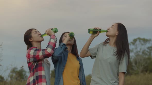 Group of young teen Asian women happy friends camping in nature having fun together drinking beer.