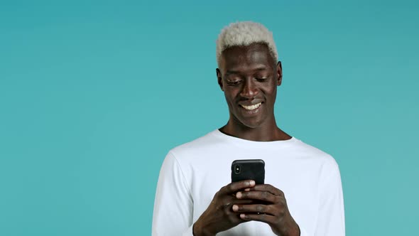 Handsome Black Man Receives Happy Notification on Mobile Phone. Guy Is Beside Himself with Surprise alt
