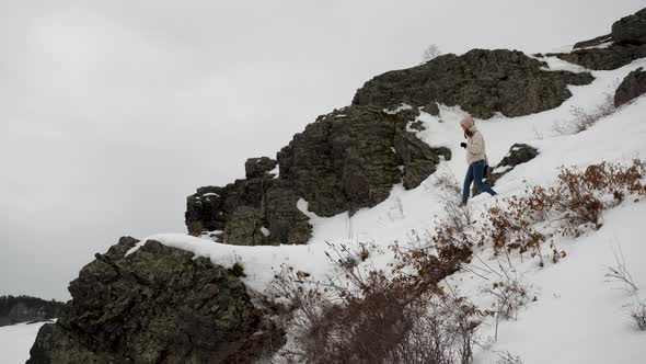 A Girl in a Sports Jacket and Trekking Shoes Descends From the Snowy Mountain