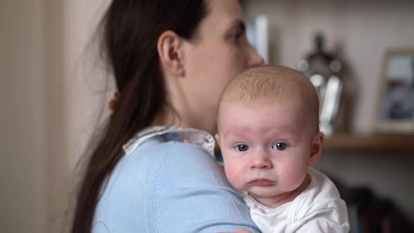 Young Mother Holding a Newborn Baby Boy in Her Arms alt