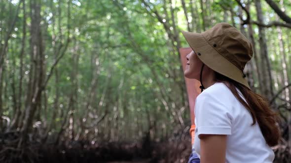 A woman sitting on a long tail boat while traveling the mangrove forest