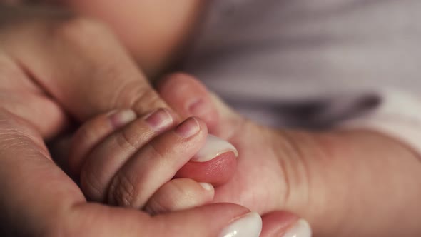 Baby Squeezes Mother's Hand with Small Fingers