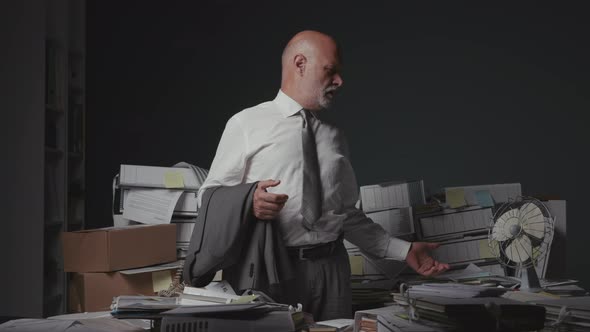 Stressed businessman surrounded by piles of paperwork