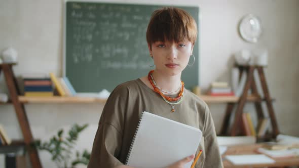 Portrait of Beautiful Girl with Copybook in Classroom alt