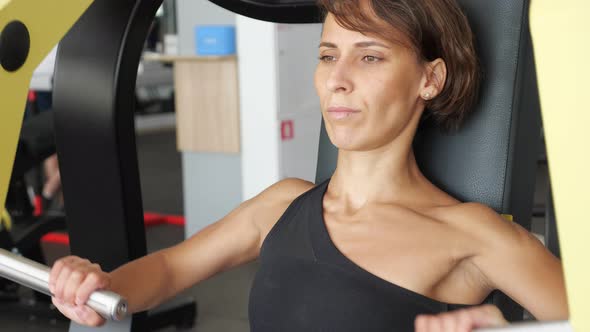 Sporty Woman is Making Exercises for Arms Muscles on Training Machine alt