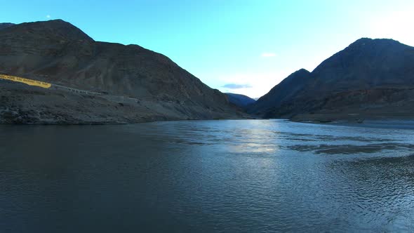 the confluence and convergence of river zanskar and indus with mountains and sun in the background f alt