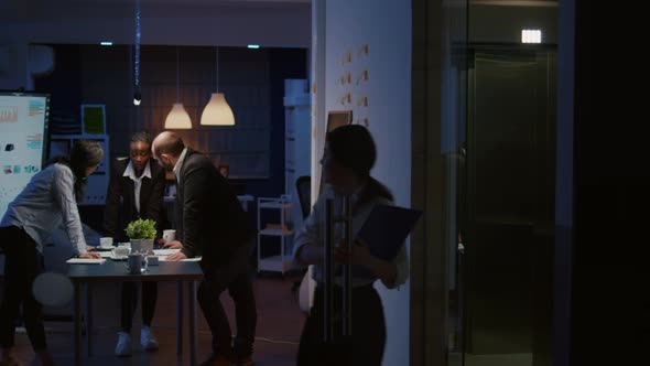 Multi Ethnic Businesspeople Lean on Conference Table Analyzing Company Strategy Ideas alt