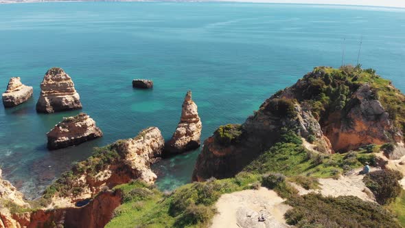 Sandstone cliffs shrouded in lush green grass encircled by Algarve Idyllic sea alt