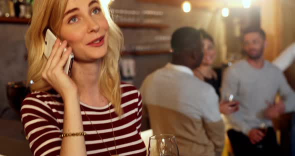 Young smiling woman talking on phone while friends interacting in background 4K alt