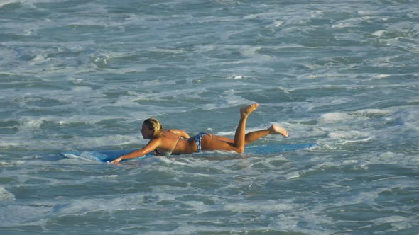 A young woman surfing in a bikini on a longboard surfboard. alt