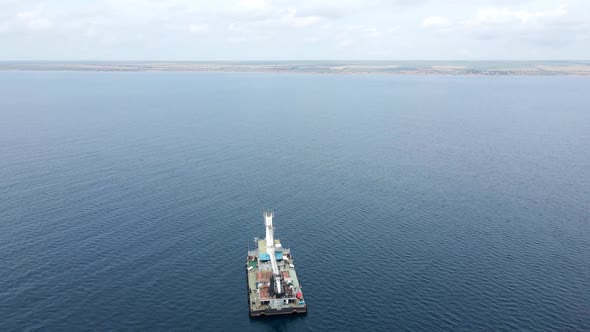 Cargo Ship with a Crane is at Sea Far From the Shore alt