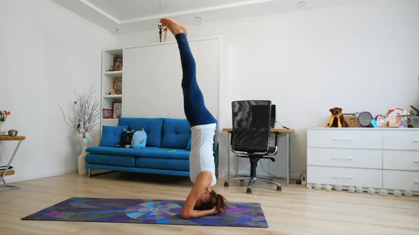Young Woman Practicing Yoga At Home, Stands In Supported Headstand