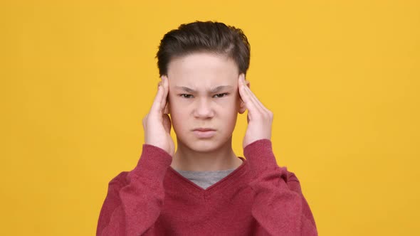 Portrait Of Boy Massaging Temples Suffering From Headache Yellow Background alt