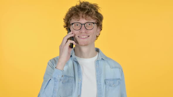 Redhead Young Man Talking on Smartphone Yellow Background alt
