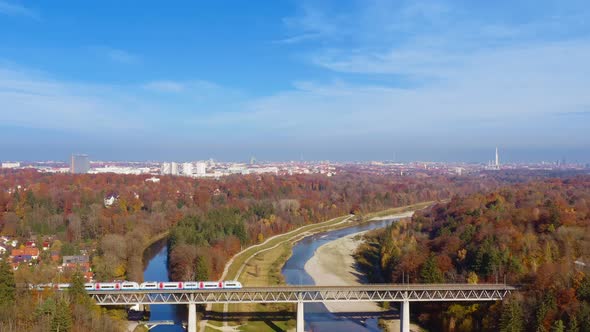 Charming travel clip - flying by drone at the autumn season over the Isar river, a train is passing alt