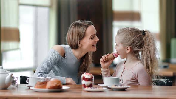 Happy Mother and Daughter Eat Dessert Together at Cafe Having Fun alt