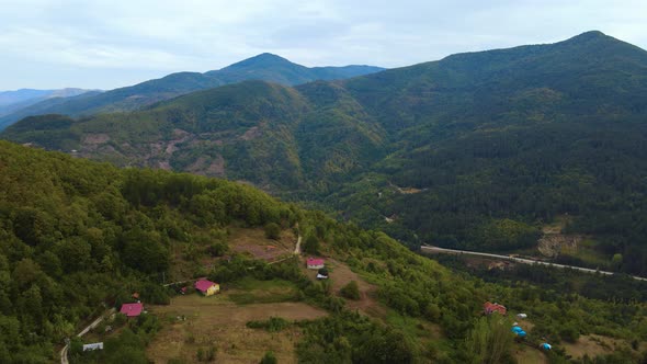 steep green mountains, deep forest and mountain road, beautiful valley and village houses alt