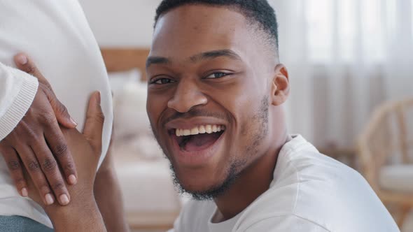 African Young Excited Man Father Husband Funny Dad Listens Pregnant Belly of Lovely Wife Woman alt