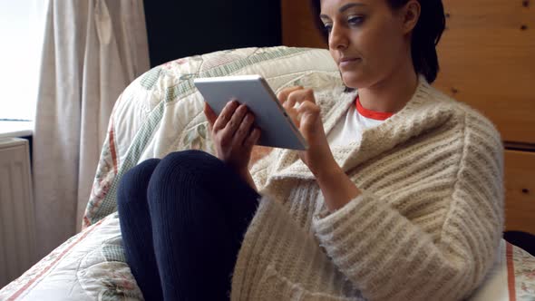 Beautiful woman using digital tablet in bedroom alt