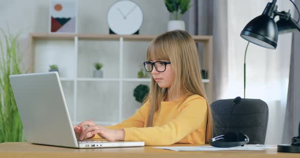 Girl in Glasses which Sitting in front of Computer and Honestly Doing Her Homework alt