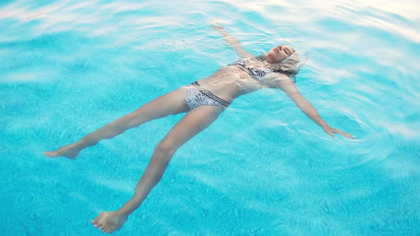 Girl in a in Leopard Swimsuit Swims in a Pool with Clear Water on Summer Vacation alt