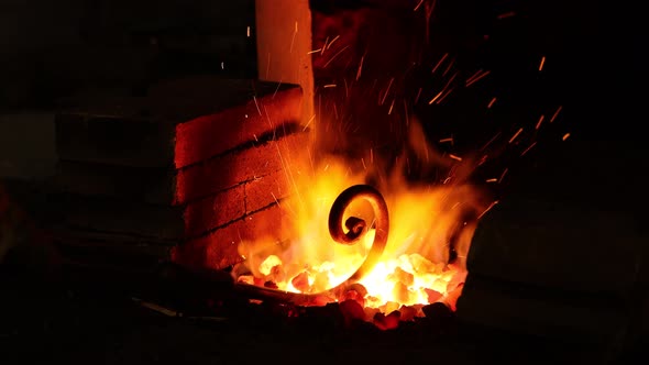 Blacksmith working in forge, heating metal in fire. 