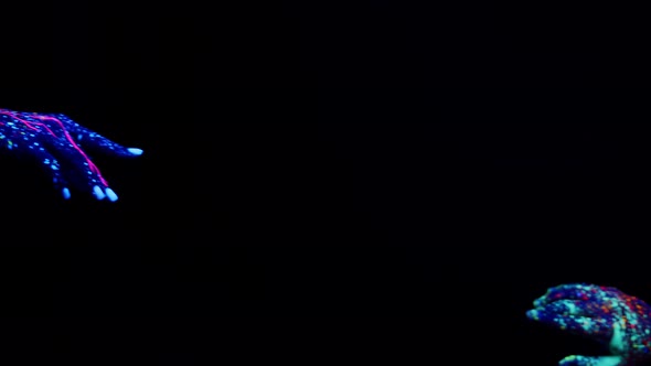 Closeup of Two Hands People Painted with Fluorescent Paints Who are Drawn to Each Other on Dark alt