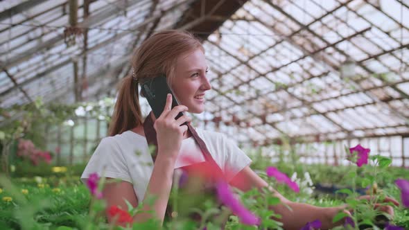 Close Up Portrait of Beautiful Joyful Female Florist Store Manager Talking on Cellphone About Plant