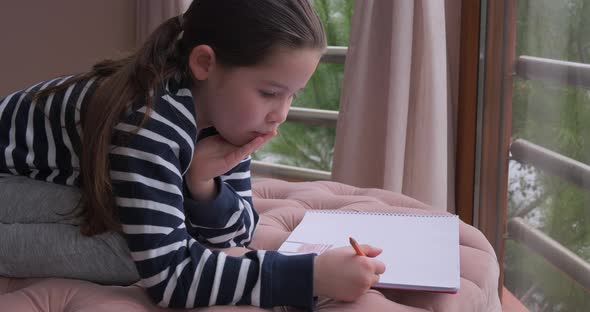 A Little Girl Drawing with Pencils at Home