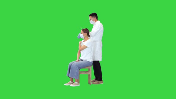 Doctor Makes an Injection of Vaccine for Covid19 to a Female Patient on a Green Screen Chroma Key alt