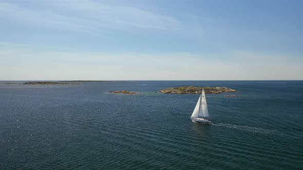 Aerial of a sailboat sailing towards the horizon in the Swedish west coast archipelagos