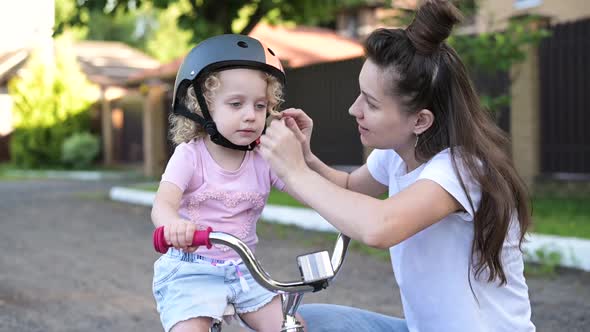 mother puts a helmet on her daughter's head before cycling in the countryside alt