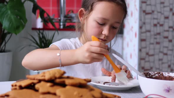 Little Girl is Takes Icing with Culinary Brush and Applies It Onto Gingerbread