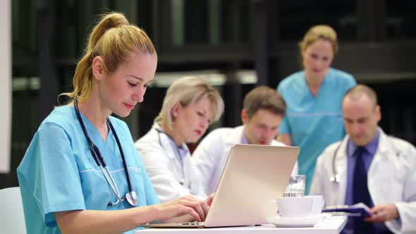 Nurse using laptop in conference room alt