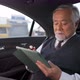 4K Senior businessman sitting on car backseat and working business plan on digital tablet