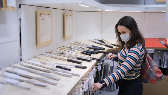 Woman Choosing Kitchen Knife in Furniture Store alt