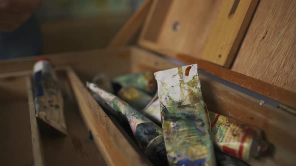 A Woman Artist with Her Hands Sorts an Easel From Old Paints for Drawing alt