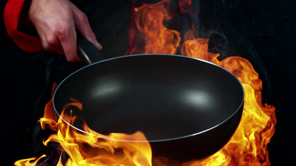 Super Slow Motion Shot of Chef Holding Empty Frying Pan and Flames at 1000Fps. alt